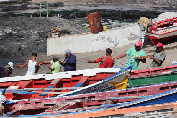 men pulling on fishing boat